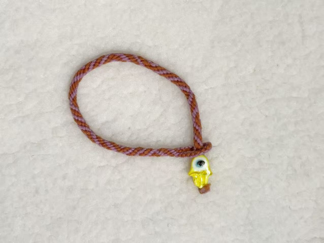 Evil Eye E01 — Rust braid · Yellow charm