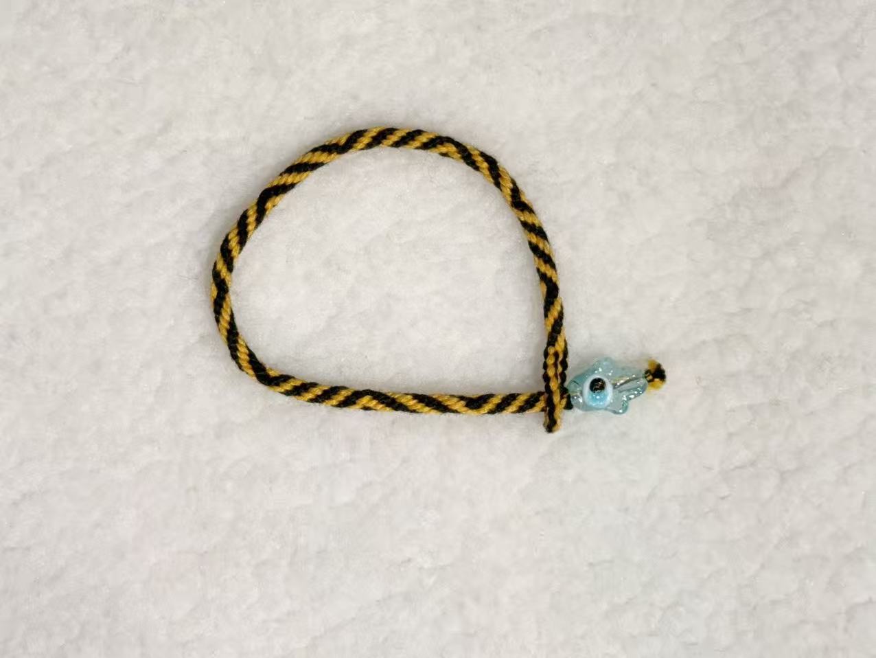 Evil Eye E07 — Black & gold · Pale charm